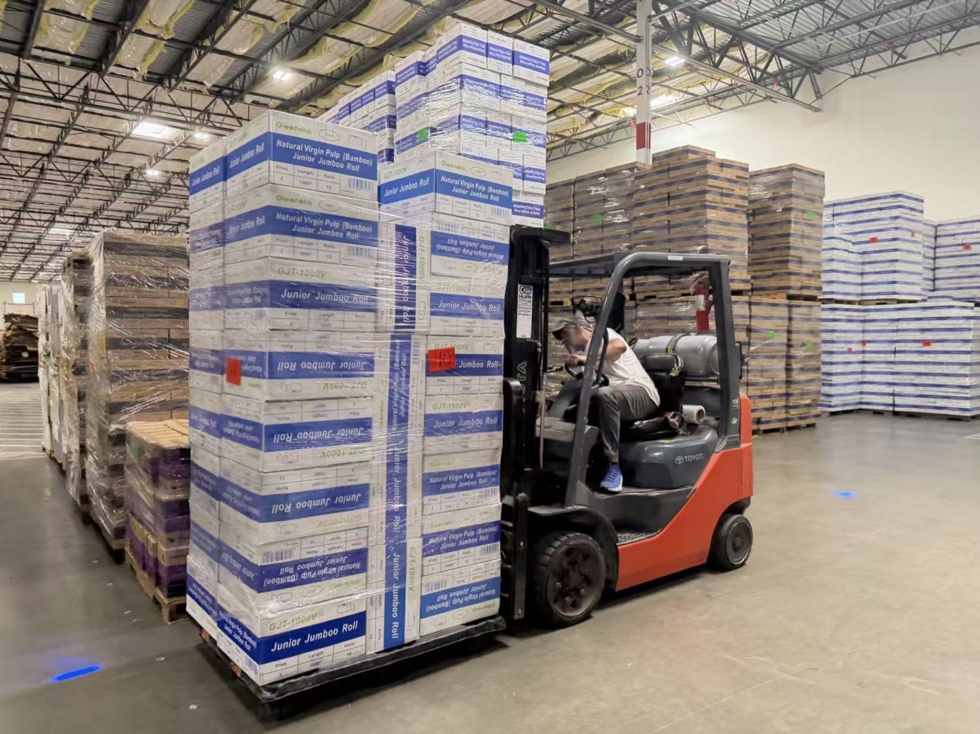 Forklift moving palletized BAYPLUS paper products in the warehouse